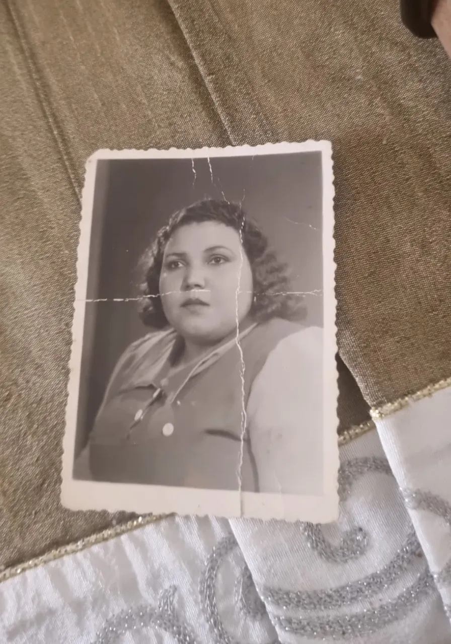 The original photograph, torn and faded, lying on a tablecloth